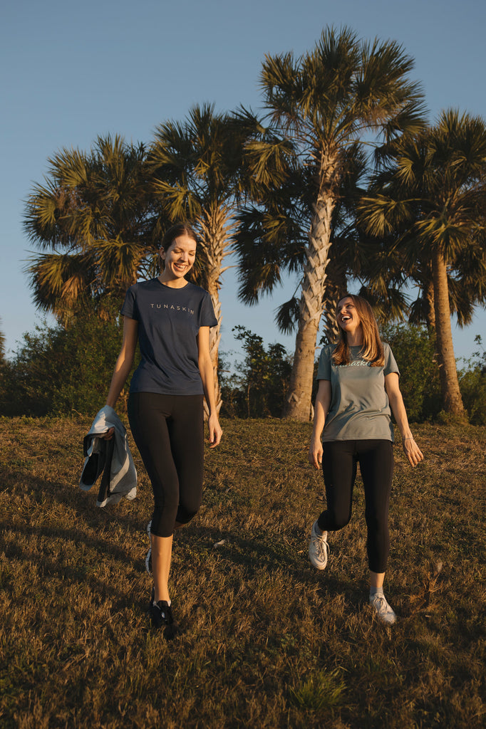 Two women walking outdoors with palm trees in the background