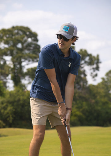 Man playing golf in navy Tunaskin polo