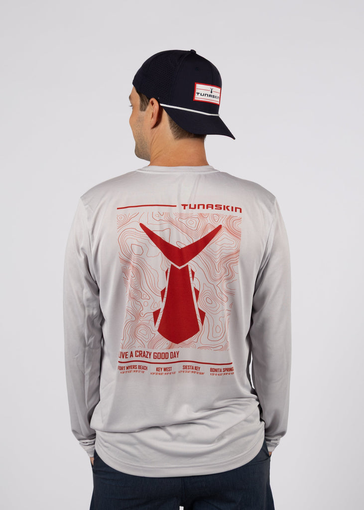 Man wearing a gray long-sleeve shirt with red graphic design on the back, standing against a white background.