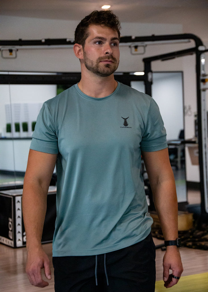 Man wearing an olive Tunaskin shirt in a gym setting
