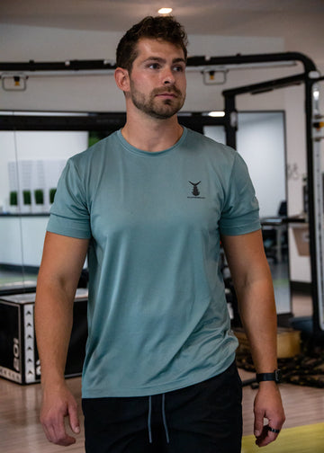 Man wearing an olive Tunaskin shirt in a gym setting