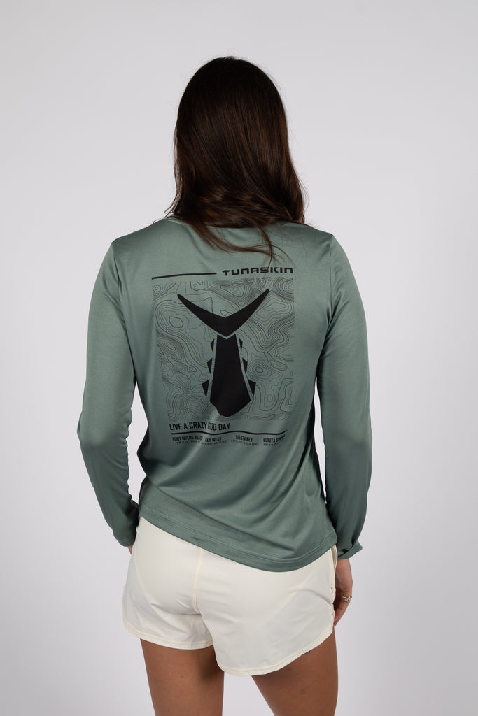Person wearing a green long-sleeve shirt with a graphic design on the back against a white background