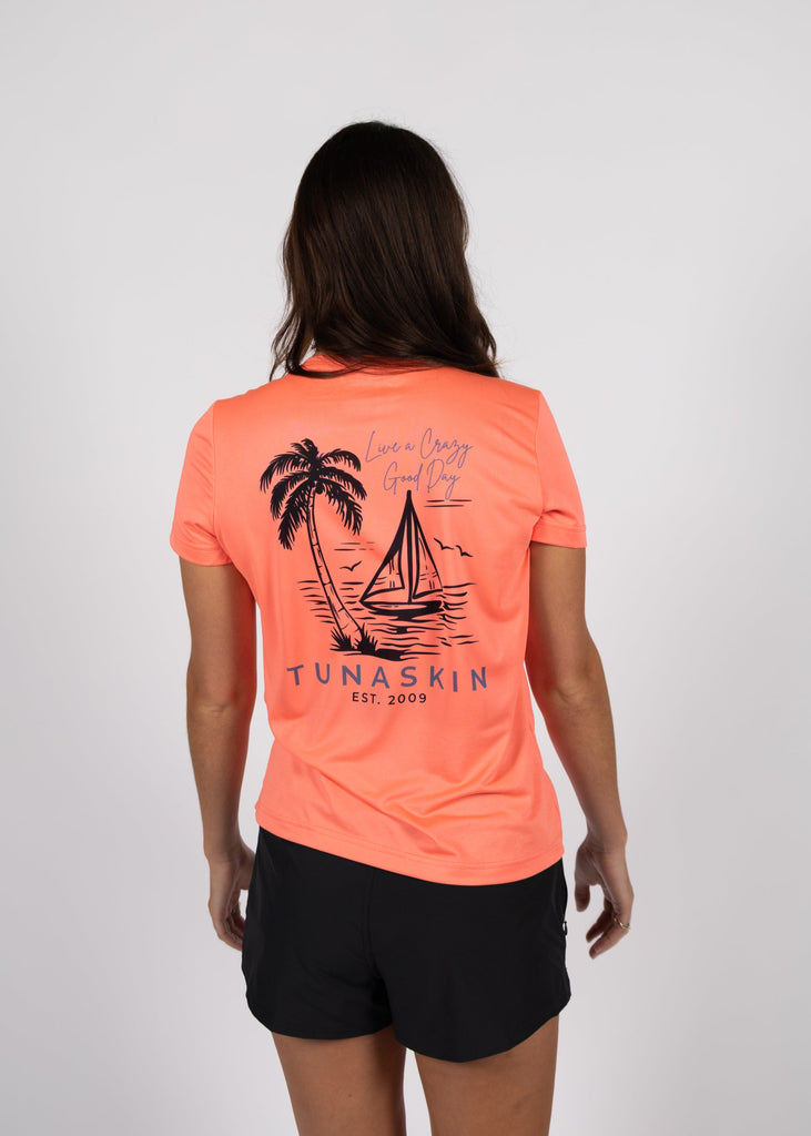 woman wearing coral v-neck short sleeve with sailboat and palm tree design on back