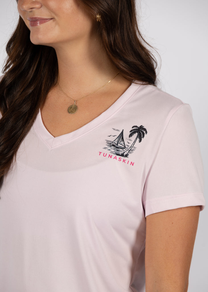 model wearing women's v-neck in flamingo pink with left chest tunaskin logo and illustration