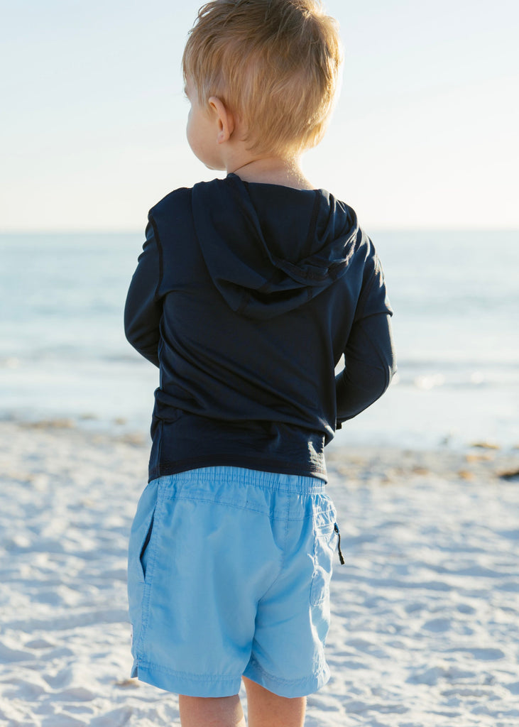 child wearing navy hoodie on beach
