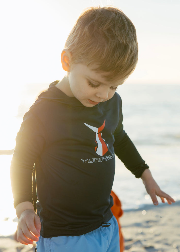 Child playing on a sandy beach with ocean in the background