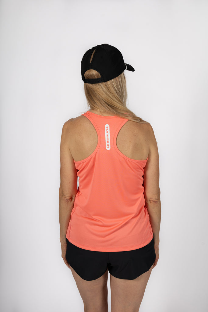 Person wearing a coral tank top and black shorts with a black cap on a white background